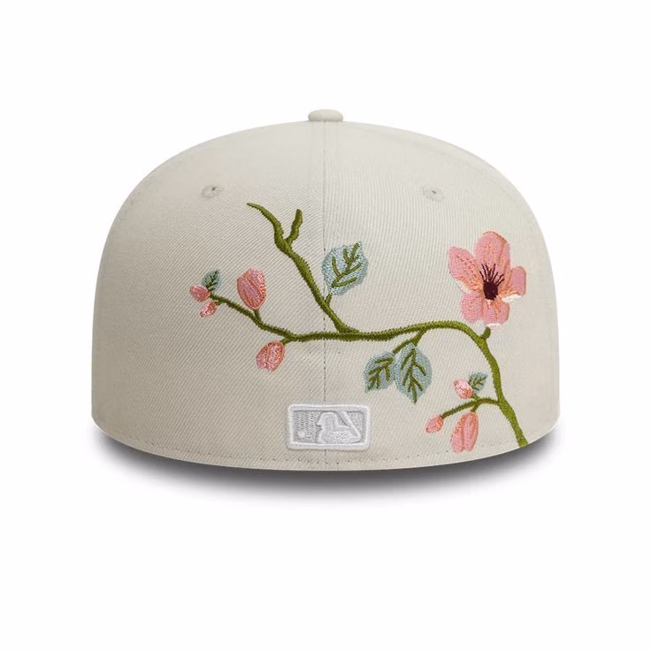 A cream fitted cap with embroidered pink flowers and green branches, viewed from the side.