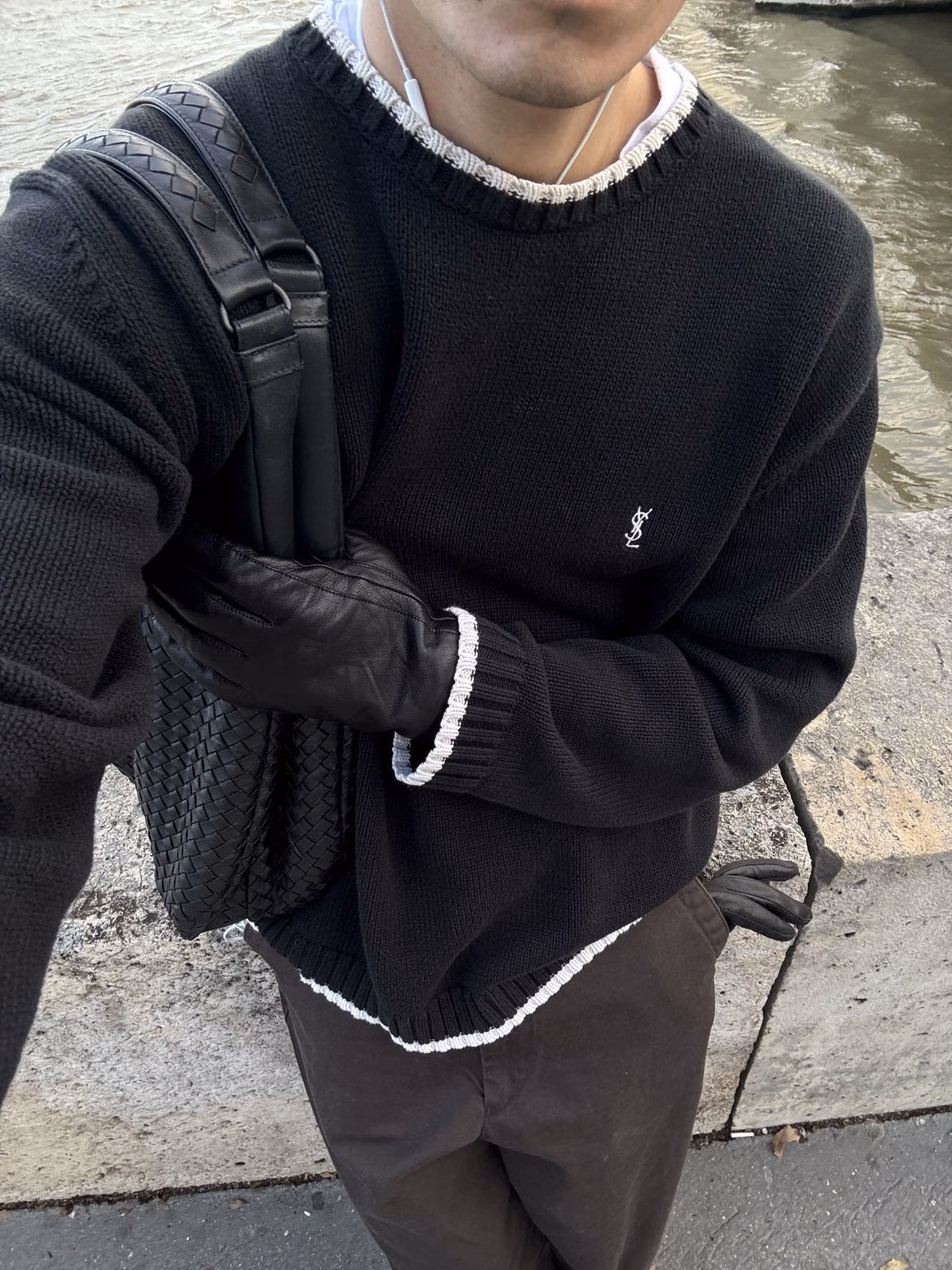 A black knit with white edging worn with a backpack and burgundy leather gloves.