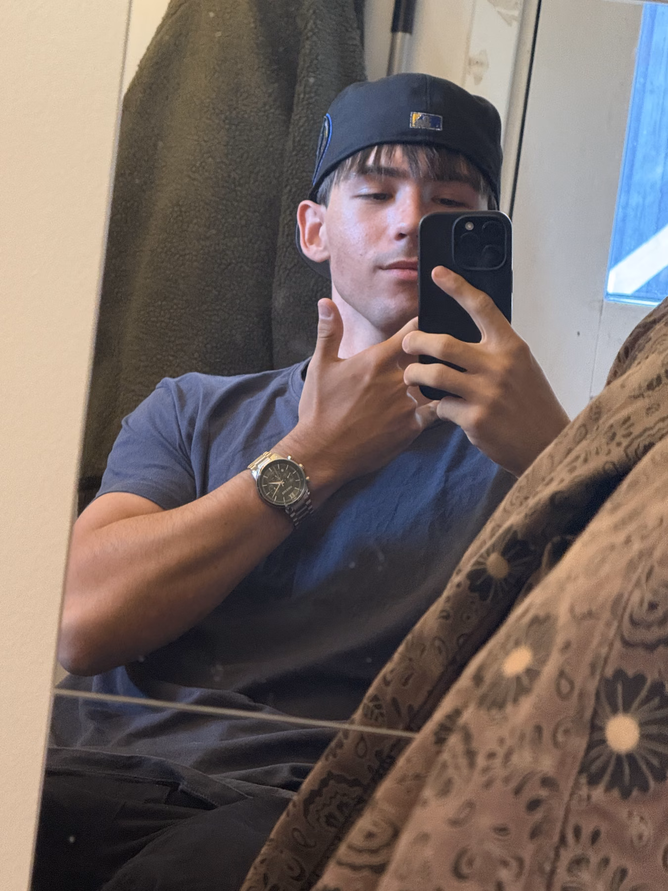 A man in a cap takes a selfie with his phone.