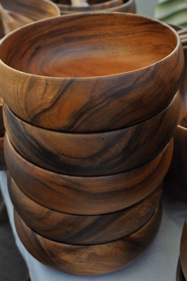 A stack of rounded bowls in dark, richly grained wood.