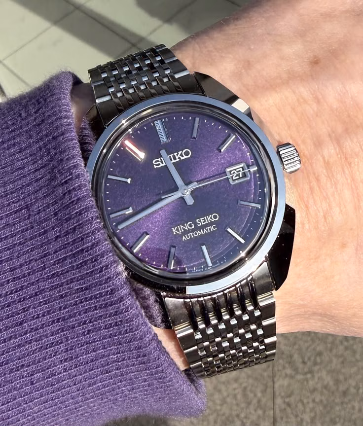 A steel King Seiko with a deep-purple dial worn over a purple knit cuff.