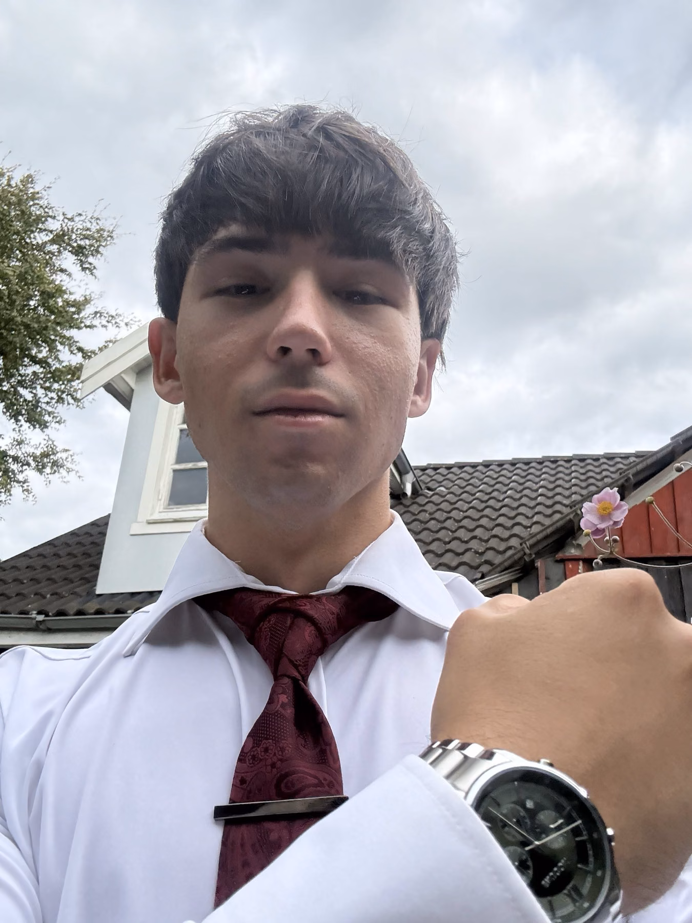 A white shirt and burgundy tie paired with a large steel watch.